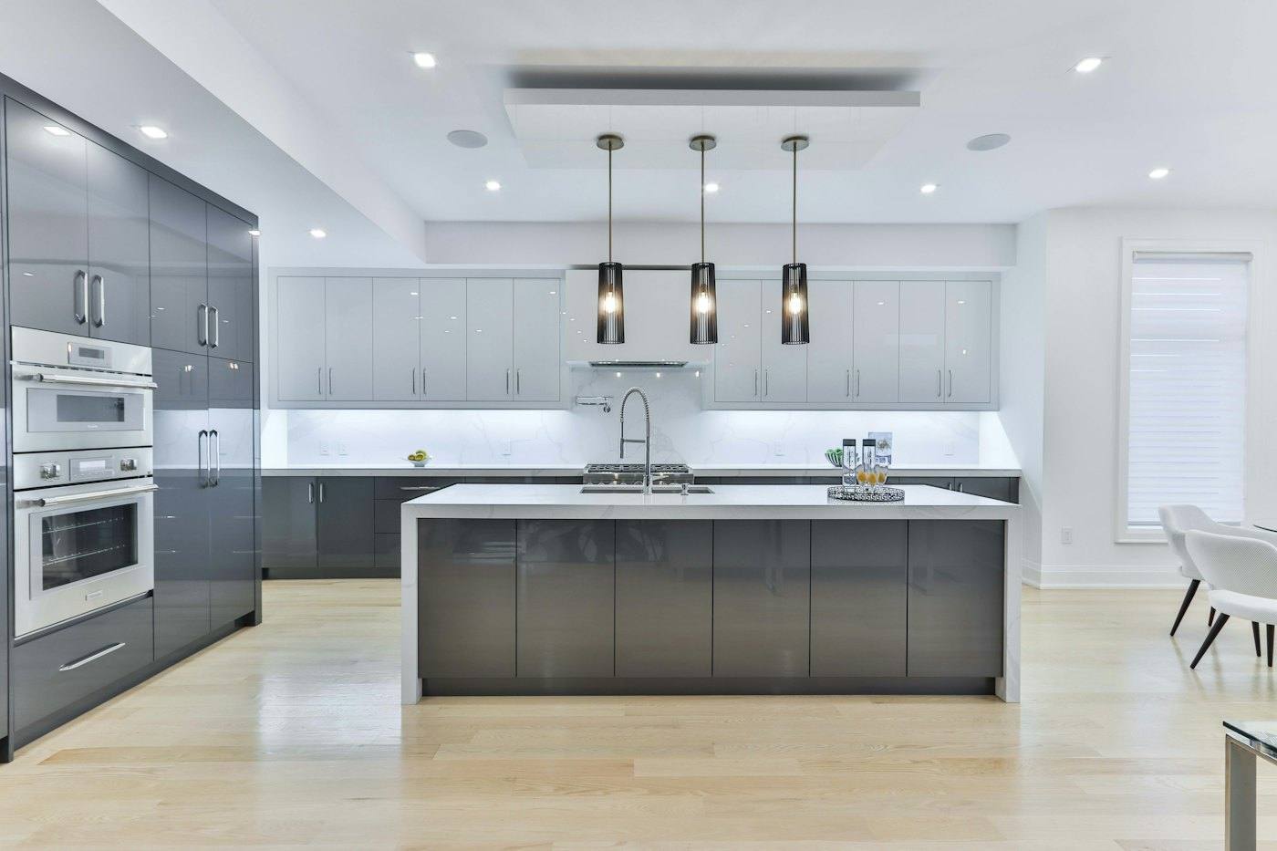 Cocina reformada con muebles grises, isla blanca y lámparas colgantes